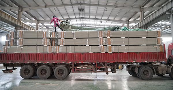 1月16日,在浙江省杭州市的一家工厂,王艳青为货物盖雨布.